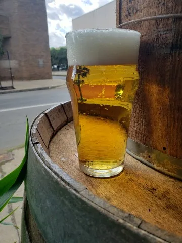 Glass of 83 Light Beer on a barrel.